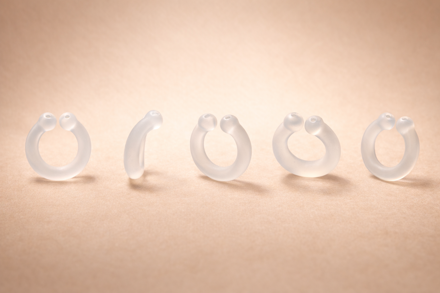 Auralis clear silicone wearable nasal aromatherapy ring shown from multiple angles on beige background