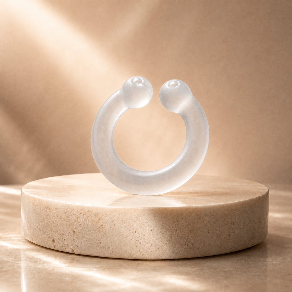 Auralis clear silicone nasal diffuser ring standing upright on a round travertine podium