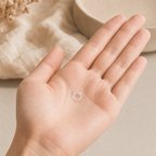 An Auralis clear silicone nasal diffuser ring resting in an open palm, showing how small it is