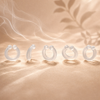 Five Auralis reusable silicone nasal diffuser rings shown from different angles on soft sand-toned fabric